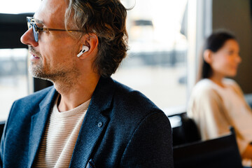 Sticker - Mature manager in earphones looking in window during offline meeting