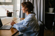 © Drobot Dean - Smiling business woman making video call via laptop while sitting in modern office