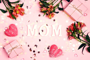 Wall Mural - Letters MOM with gifts, flowers and hearts on a pink background.