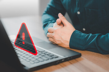 Wall Mural - Adult man using a computer laptop with triangle caution warning sign for notification error. Concept technology of computer virus detected, personal data protection, network security and maintenance.