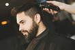 © New Africa - Professional hairdresser working with bearded client in barbershop