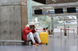 Sad African American man upset at airport his flight is delayed. Depressed traveler male waiting for a plane sitting in empty terminal with baggage. Exhausted guy on a long night connection at airport