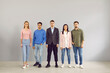 © Studio Romantic - Group portrait of young people in smart casual clothes. Team of 5 unsmiling corporate employees in jumpers, jackets, shirts, trousers and jeans standing in studio. Work dress code in office concept