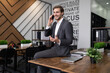 © Ivan Traimak - man in a business suit talking on the phone in the office sitting on the table