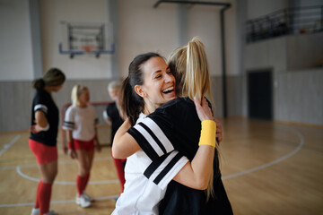 Sticker - Group of young and old women, sports team players, in gym celebrating victory, hugging.