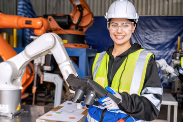 young female asian service engineer holding robot controller operate robot arm automation factory