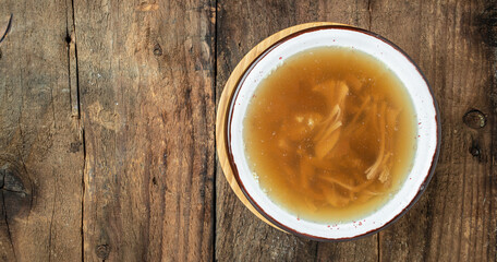 Canvas Print - Broth in Bowl with meat pork knuckle on a wooden background, Long banner format. top view