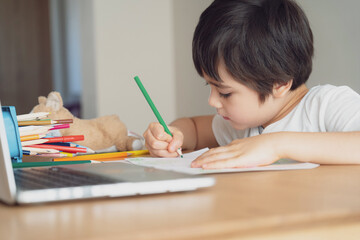 Education concept,School kid using grey colour pen drawing or sketching on paper,Portrait  boy siting on table doing homework in living room,Child enjoy art and craft activity at home on weekend