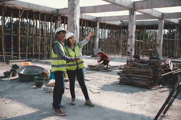 Two specialists inspect commercial, Industrial building construction site. Real estate project with civil engineer, designing commercial buildings on paper. Skyscraper concrete formwork frames.