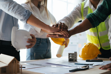 Construction workers, architects and engineers shake hands after completing an agreement in an office facility, successful cooperation concept.