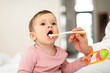 © Prostock-studio - Baby feeding concept. Cute little infant girl opening mouth and eating from spoon, mother giving healthy food to child