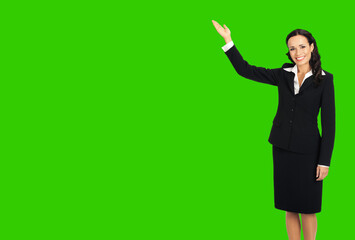 Sticker - Full body of happy smiling attractive woman in black confident suit, showing copy space. Business concept. Brunette businesswoman. Green chroma key background.