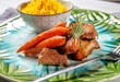 Pieces of pork with carrots and rice.