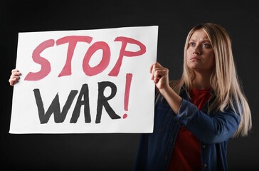 Wall Mural - Sad woman holding poster with words Stop War on black background