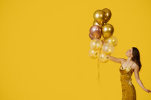 Holiday Celebration Concept. Young Woman In Romantic Dress Holding Bunch Of Balloons, Yellow Background, Free Space