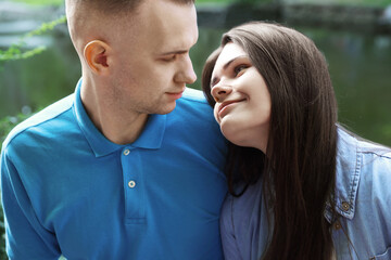 Poster - Affectionate young couple sitting together in park, closeup