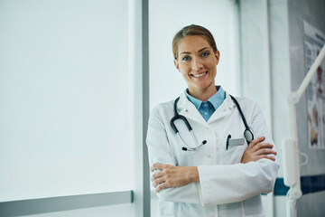 Wall Mural - Happy medical expert with her arms crossed at clinic looking at camera.