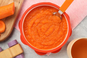 Healthy baby food. Bowl with delicious carrot puree on light grey marble table, flat lay