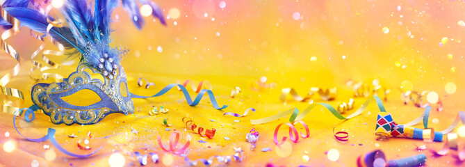 Wall Mural - carnival party - venetian mask on yellow satin with shiny streamers on abstract defocused bokeh ligh