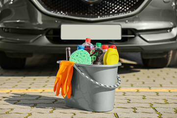 Wall Mural - Car cleaning products in bucket near automobile outdoors on sunny day