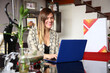 © JAHF - Mujer latina elegante y sonriente sentada frente a ordenador portátil, concepto de conferencia online, teletrabajo, clases virtuales, transmisión en vivo.