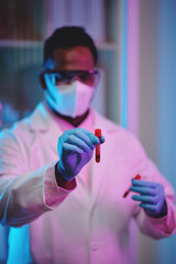 Wall Mural - Scientist in gloves and medical mask holding test-tubes with blood samples