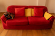© ninika - on a parquet floor three seater sofa upholstered in red fabric and trimmed with two red cushions, three yellow cushions and an English cushion