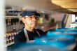 © kleberpicui - Elderly man working in a hardware store restocking items on shelves. Small business concept.