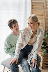 Wall Mural - pleased young woman sitting with happy boyfriend on bed bench.