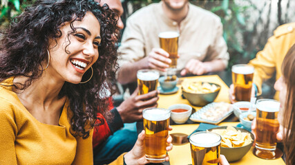 Happy friends cheering beer glasses at brewery pub restaurant - Group of young people enjoying happy hour celebrating party outdoors - Beverage life style concept with guys and girls hanging out