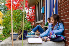 Two Children Read Together Outside On Their Front Stoop
