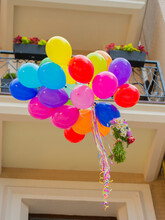 Balloons With A Bouquet Of Flowers On The Background Of The House.flying Colorful Balloons With A Bouquet Of Flowers On The Background Of A Building With A Balcony