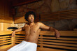 © Wavebreak Media - Tranquil biracial man wearing towel relaxing on bench in sauna, copy space
