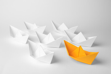 Sticker - Group of paper boats following orange one on white background. Leadership concept