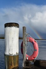 A Lifesaver Buoy At The End Of A Jetty Pier Boardwalk With A Rainbow In The Blue Sky In Tasmania, Australia.