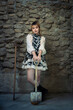 © pomphotothailand - Portrait fashion of a young Asian girl in a beautiful dress holding farmer tools and shovels in her hand with the walls of the room made of stones background. Gardening and farmer dark tone concept.