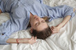 © triocean - Portrait og beautiful natural looking brunette woman in blue cotton pajama shirt laying on the bed