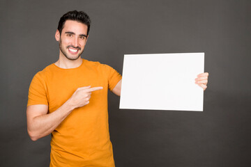 Wall Mural - Smiley man holding and pointing a blank panel