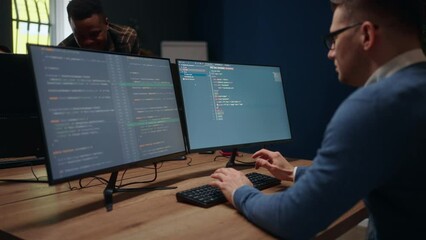 database architect is writing computer code, view through shoulder on display, male data scientist