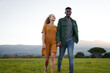 © StratfordProductions - Happy young multiracial couple smiling and holding hands while walking through field