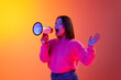 Leinwandbild Motiv News, information. Young girl in pink sweater talking in megaphone over gradient orange background in neon light. Concept of emotions, facial expression, youth, lifestyle, inspiration, sales, ad