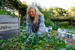 © StratfordProductions - Happy young caucasian woman in checked shirt smiling next to plants in garden center
