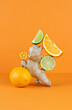 © Amore Sea - Balancing citrus fruits on the table. Citrus pyramid: lime, orange, ginger and lemon on an orange background. Ingredients for preparing a drink for colds and flu. Copy Space.