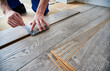 © anatoliy_gleb - Man preparing laminate plank for floor installation in apartment under renovation. Close up of male worker using metal construction ruler and pen while drawing line on laminate flooring board.