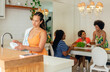 © Vergani Fotografia - brazilian woman washing dish and friends serving food in the kitchen
