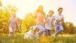 © Robert Kneschke - Family with two children and a dog is running in the garden