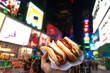 Holding two hot dogs in NYC on the Times Square