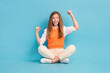 Full length photo of cut pretty overjoyed lady sitting floor raise fist isolated on blue color background