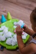 Creative indoor snow activities for kids. Toddler playing with snow at home during cold snowy winter days, cropped photo