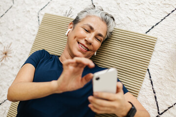 Browsing the internet on a workout break, senior woman watching a fitness tutorial on her smartphone